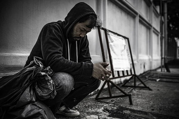 Asyalı adam yan yolda evsiz. Bir yabancı, ailesi olmadığı için yolda tek başına yaşamak zorundadır..