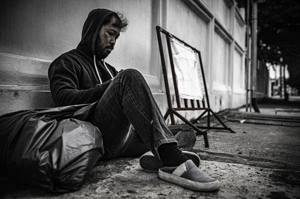 Asyalı adam yan yolda evsiz. Bir yabancı, ailesi olmadığı için yolda tek başına yaşamak zorundadır..