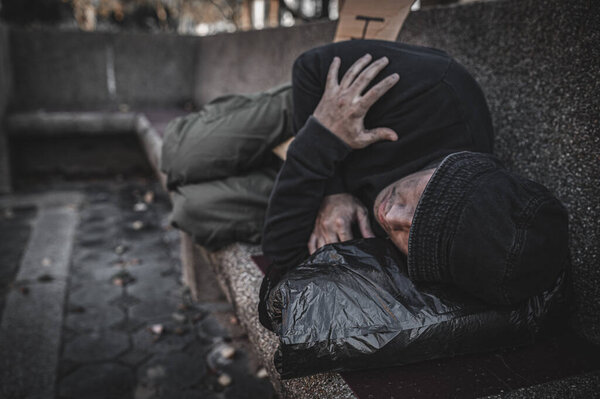 Asian man is homeless at the side road. A stranger has to live on the road alone because he has no family.
