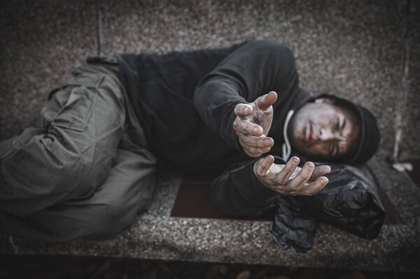 Asian man is homeless at the side road. A stranger has to live on the road alone because he has no family.