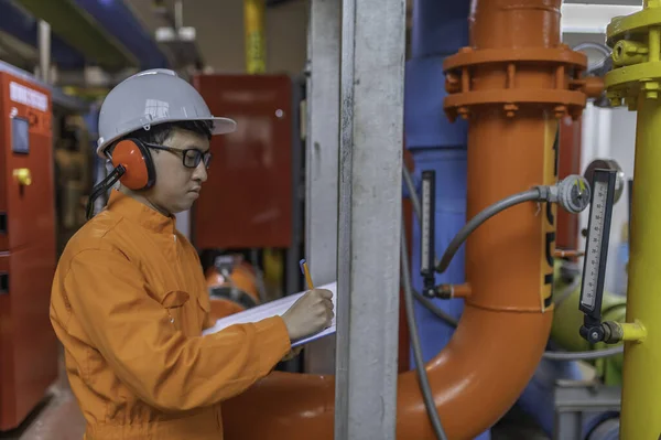 Maintenance technician at a heating plant. Petrochemical worker supervise the operation of gas and oil pipelines in the factory. Engineer put hearing protector At room with many pipes