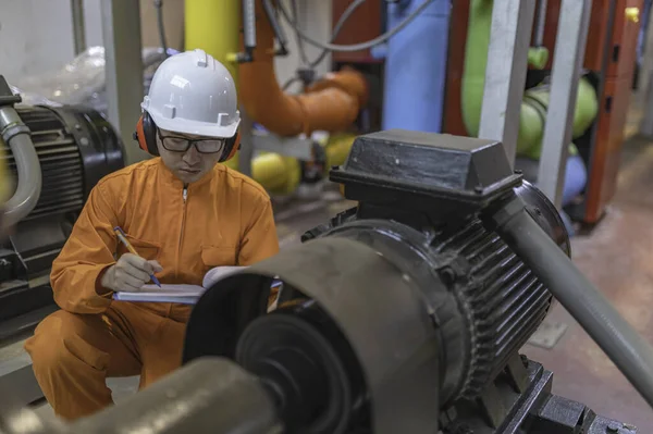 Maintenance technician at a heating plant. Petrochemical worker supervise the operation of gas and oil pipelines in the factory. Engineer put hearing protector At room with many pipes