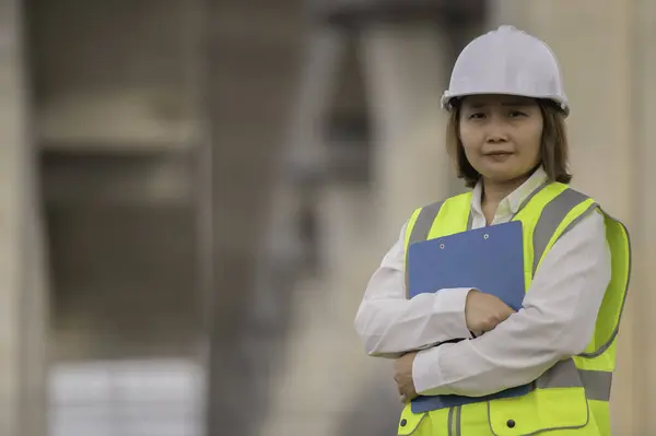 An Asian female engineer works at a motorway bridge construction site. Civil worker inspecting work on crossing construction
