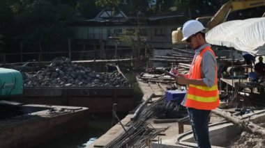 İnşaat mühendisi nehrin üzerinde köprü inşaatında çalışıyor. İnşaat mühendisi denetleme işi. Foreman bir inşaat alanında çalışıyor.