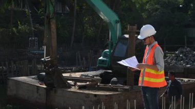 İnşaat mühendisi nehrin üzerinde köprü inşaatında çalışıyor. İnşaat mühendisi denetleme işi. Foreman bir inşaat alanında çalışıyor.