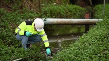 Koruyucu giysili ve koruyucu eldivenli genç adam su kirliliği seviyesini sıvılarda test ediyor