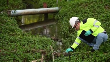 Koruyucu giysili ve koruyucu eldivenli genç adam su kirliliği seviyesini sıvılarda test ediyor