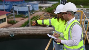 Miğferler ve bardaklar üzerinde çalışan erkek ve kadın mühendis. Atık su kavramı