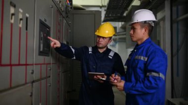 Elektrik mühendisleri endüstriyel kontrol odalarındaki elektrik sistemi arızalarını çözmek için birlikte çalışıyorlar..
