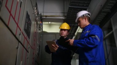 Elektrik mühendisleri endüstriyel kontrol odalarındaki elektrik sistemi arızalarını çözmek için birlikte çalışıyorlar..