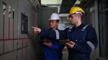 Elektrik mühendisleri endüstriyel kontrol odalarındaki elektrik sistemi arızalarını çözmek için birlikte çalışıyorlar..