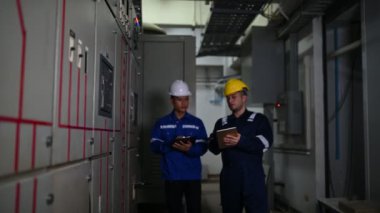 Elektrik mühendisleri endüstriyel kontrol odalarındaki elektrik sistemi arızalarını çözmek için birlikte çalışıyorlar..