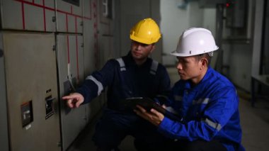 Elektrik mühendisleri endüstriyel kontrol odalarındaki elektrik sistemi arızalarını çözmek için birlikte çalışıyorlar..