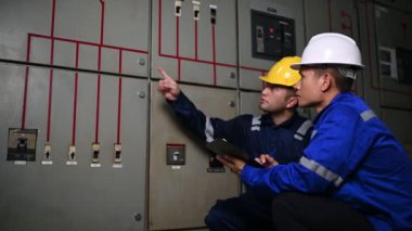 Elektrik mühendisleri endüstriyel kontrol odalarındaki elektrik sistemi arızalarını çözmek için birlikte çalışıyorlar..