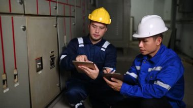 Elektrik mühendisleri endüstriyel kontrol odalarındaki elektrik sistemi arızalarını çözmek için birlikte çalışıyorlar..