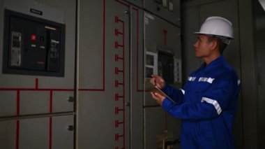 Elektrik mühendisi endüstriyel kontrol odasındaki elektrik sistemi arızalarını çözüyor..