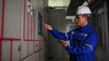 Elektrik mühendisi endüstriyel kontrol odasındaki elektrik sistemi arızalarını çözüyor..
