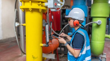 Bir ısıtma tesisinde bakım teknisyeni, Petrokimya işçileri fabrikadaki gaz ve petrol boru hatlarının işleyişini denetliyor, mühendisler işitme koruyucularını birçok boruyla aynı odaya koyuyorlar.