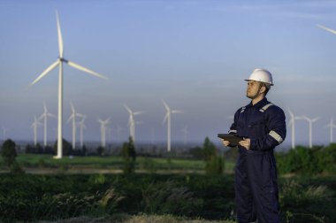Tayland 'da, dağdaki rüzgar türbini çiftliği güç jeneratörü istasyonunda çalışan mühendisler ve çalışan mühendisler, teknisyen erkek ve kadın iş hakkında tartışıyorlar.