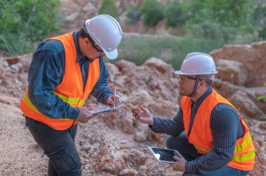 Benimkini araştıran bir jeolog, madenciler mineralleri aramak için toprak örnekleri topluyor..