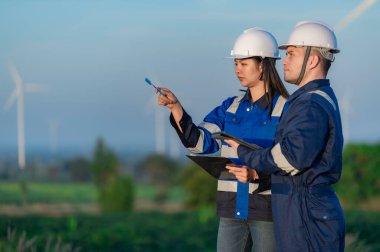 Tayland 'da, dağdaki rüzgar türbini çiftliği güç jeneratörü istasyonunda çalışan mühendisler ve çalışan mühendisler, teknisyen erkek ve kadın iş hakkında tartışıyorlar.