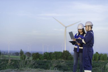 Tayland 'da, dağdaki rüzgar türbini çiftliği güç jeneratörü istasyonunda çalışan mühendisler ve çalışan mühendisler, teknisyen erkek ve kadın iş hakkında tartışıyorlar.