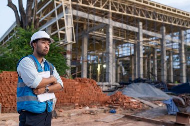 Tayland 'da büyük bir inşaat projesinin şantiyesinde çalışan Asyalı mühendis inşaat alanında fazla mesai yapıyor.