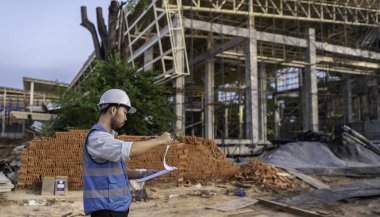 Tayland 'da büyük bir inşaat projesinin şantiyesinde çalışan Asyalı mühendis inşaat alanında fazla mesai yapıyor.