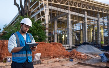 Tayland 'da büyük bir inşaat projesinin şantiyesinde çalışan Asyalı mühendis inşaat alanında fazla mesai yapıyor.