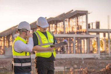 Tayland 'da büyük bir inşaat projesinin şantiyesinde çalışan iki Asyalı mühendis şantiyede fazla mesai, şantiyede çalışan bir mühendis diski.