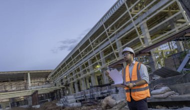 Tayland 'da büyük bir inşaat projesinin şantiyesinde çalışan Asyalı mühendis inşaat alanında fazla mesai yapıyor.