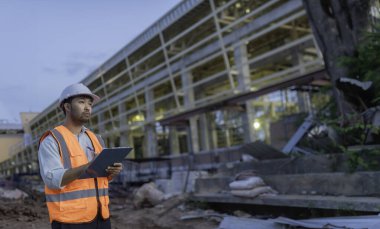 Tayland 'da büyük bir inşaat projesinin şantiyesinde çalışan Asyalı mühendis inşaat alanında fazla mesai yapıyor.