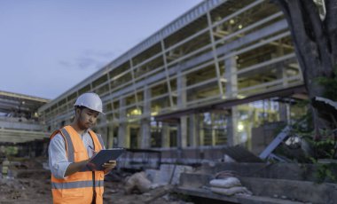 Tayland 'da büyük bir inşaat projesinin şantiyesinde çalışan Asyalı mühendis inşaat alanında fazla mesai yapıyor.