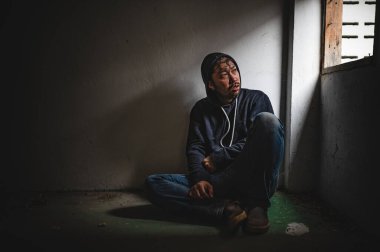 Asyalı bir bağımlı, ıssız bir yerde uyuşturucu bağımlısı, bu dünyada kendini yalnız hisseden bir keş, odanın bir köşesinde oturan üzgün bir genç, insanlar stresli ve depresyondalar.