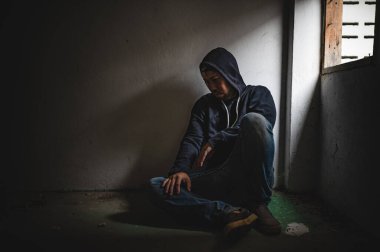 Asyalı bir bağımlı, ıssız bir yerde uyuşturucu bağımlısı, bu dünyada kendini yalnız hisseden bir keş, odanın bir köşesinde oturan üzgün bir genç, insanlar stresli ve depresyondalar.