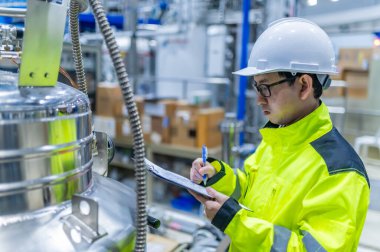 Tayland 'da, ameliyathanede çalışan Asyalı mühendis kask takıyor, özenle ve sabırla çalışıyor, hidrojen tankının valf düzenleyicisini kontrol ediyor..