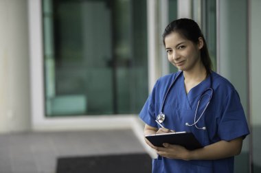 Klinikte çalışan genç Asyalı hemşire, bir hastanede doktor portresi.