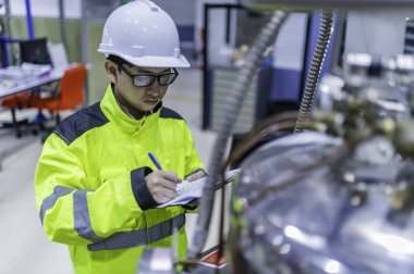 Tayland 'da, ameliyathanede çalışan Asyalı mühendis kask takıyor, özenle ve sabırla çalışıyor, hidrojen tankının valf düzenleyicisini kontrol ediyor..