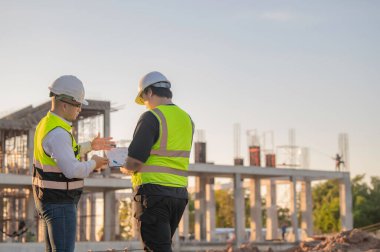Tayland 'da büyük bir inşaat projesinin şantiyesinde çalışan iki Asyalı mühendis şantiyede fazla mesai, şantiyede çalışan bir mühendis diski.