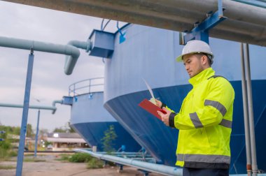 Mühendis ve teknisyen bakımı, su pompası ve basınç göstergesi, su tedarikçisinin teknik verilerini kontrol ediyor.