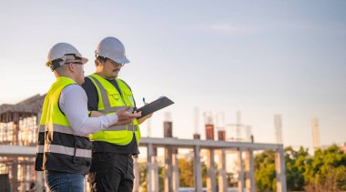 Tayland 'da büyük bir inşaat projesinin şantiyesinde çalışan iki Asyalı mühendis şantiyede fazla mesai, şantiyede çalışan bir mühendis diski.