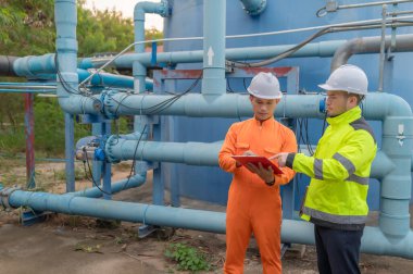 Mühendis ve teknisyen bakımı, su pompası ve basınç göstergesi, su tedarikçisinin teknik verilerini kontrol ediyor.
