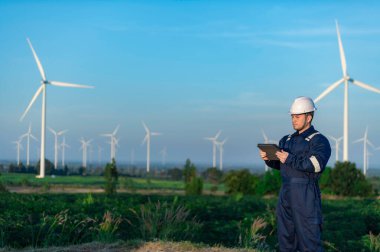 Rüzgar türbini tarım enerji jeneratörü istasyonunda çalışan mühendisler raporu tutuyor.