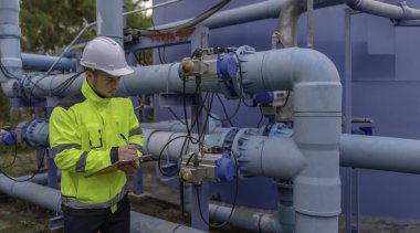 Mühendis ve teknisyen bakımı, su pompası ve basınç göstergesi, su tedarikçisinin teknik verilerini kontrol ediyor.