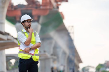 Asyalı bir erkek mühendis otoban köprüsü şantiyesinde çalışıyor, inşaat çalışmalarını denetleyen bir memur, yüksek hızlı demiryolu şantiyesinde çalışan bir denetçi.