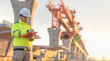 Asyalı bir erkek mühendis otoban köprüsü şantiyesinde çalışıyor, inşaat çalışmalarını denetleyen bir memur, yüksek hızlı demiryolu şantiyesinde çalışan bir denetçi.