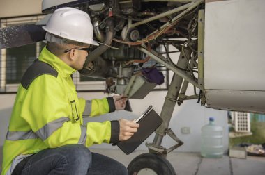 Teknisyen uçağın motorunu tamir ediyor, kadın uzay mühendisliği uçak motorlarını kontrol ediyor, Asyalı tamirci uçak motorlarını kontrol ediyor.