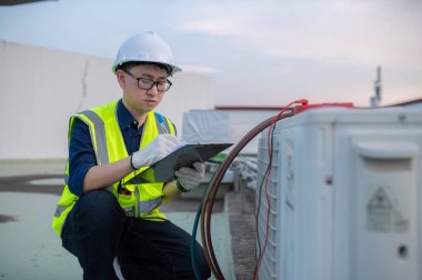 Soğutma ve Havalandırma Mühendisliği Tesis Soğutma Sorunlarını Tesis Tesislerinde, Elektrik Bakımı Yoğunlaşması Büyük endüstriyel binaların çatısında, Mühendis kontrol altında endüstriyel soğutma kulesi kliması 
