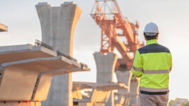 Asyalı bir erkek mühendis otoban köprüsü şantiyesinde çalışıyor, inşaat çalışmalarını denetleyen bir memur, yüksek hızlı demiryolu şantiyesinde çalışan bir denetçi.