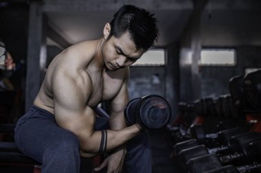 Spor salonunda çalışan yakışıklı, ağırlık kaldıran Asyalı bir adam spor müsabakası için ağırlık kaldırıyor sırt kası çalıştırmak için halteri kaldırıyor.